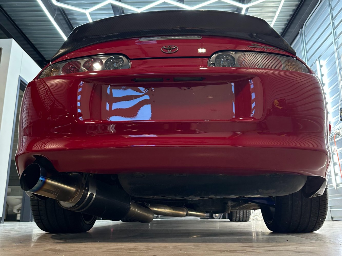 MK4 Supra Paint Correction Under LED Shop Lighting Rear view of red MK4 Toyota Supra after paint correction under LED detailing lights