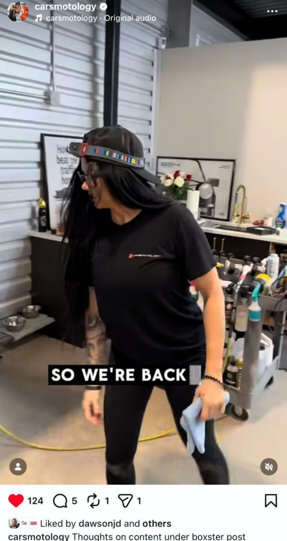 Jennifer from Carsmotology speaking inside the detailing shop while holding a microfiber towel.