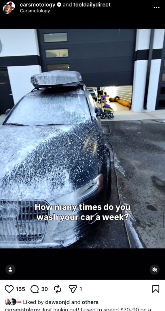 Car being covered in thick foam during the car washing process outside a detailing shop.