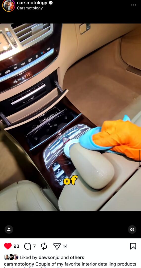 Interior car detailing using microfiber towel on center console controls.