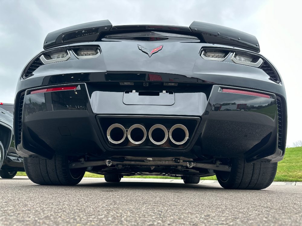 Rear view of a black C7 Corvette showing quad exhaust tips and a glossy protected rear fascia in Boerne, TX