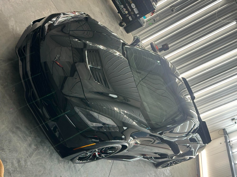 Black C7 Corvette hood and fenders showing swirl-free clarity after a two-stage Rupes paint correction