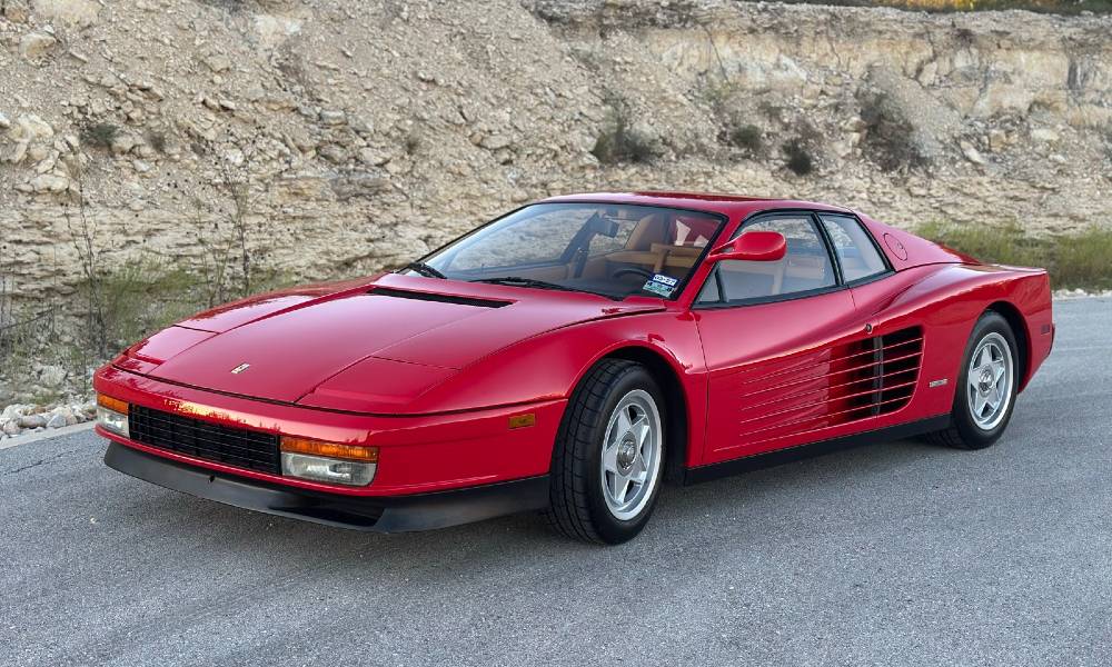 Red 1986 Ferrari Testarossa with a glossy paint-corrected and ceramic-coated finish, front three-quarter view against a Texas Hill Country limestone backdrop, detailed by Carsmotology in Boerne TX