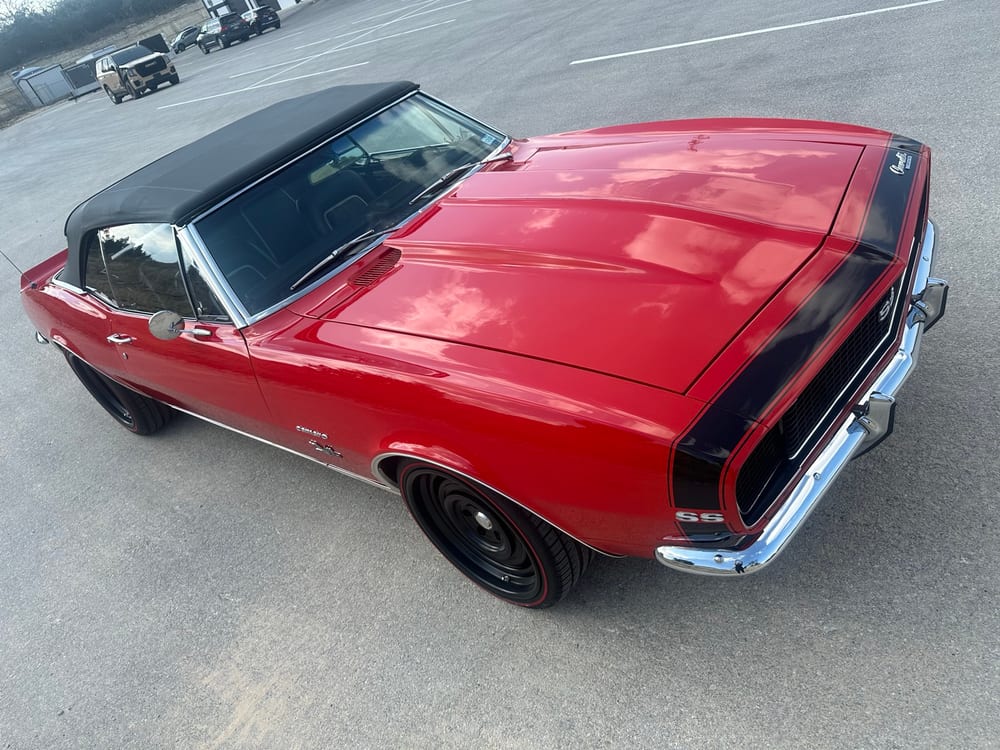 Overhead view of a red 1967 Camaro SS hood reflecting clouds with swirl-free paint after paint correction and ceramic coating