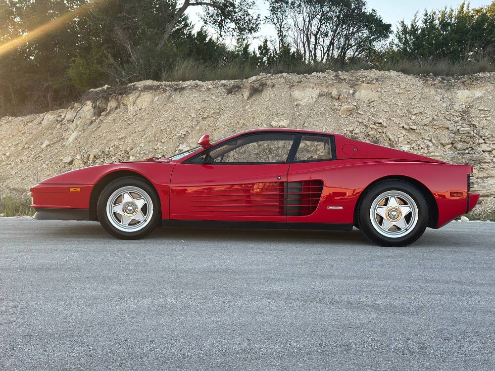 Red Ferrari Testarossa front three-quarter parked against a limestone cliff in the Texas Hill Country after ceramic coating