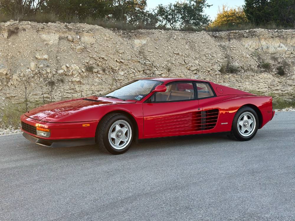 Rear three-quarter of a red Ferrari Testarossa showing the Testarossa badge and tail louvers with corrected glossy paint