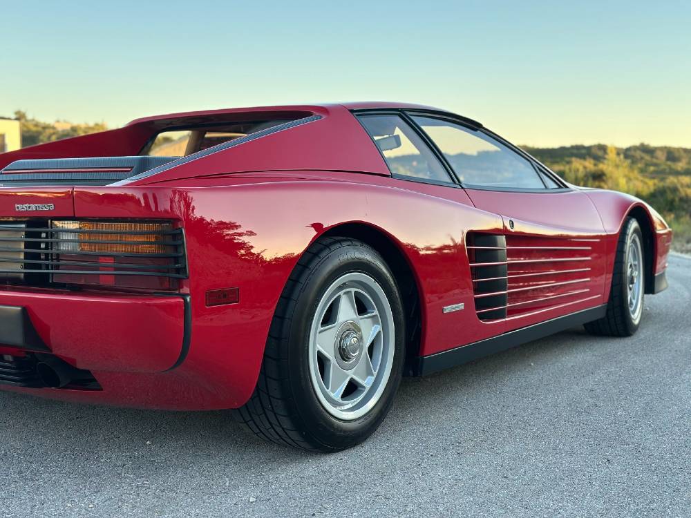 Rear quarter and five-spily alloy wheel of a red Ferrari Testarossa with glossy ceramic-coated paint at golden hour