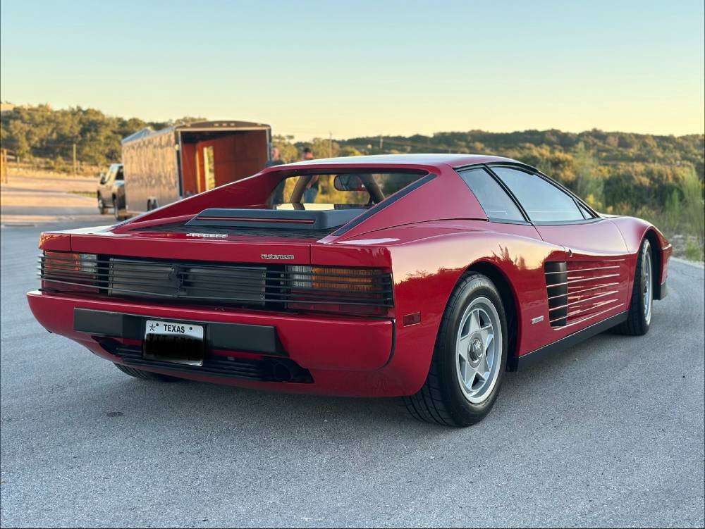 Red Ferrari Testarossa rear three-quarter with an enclosed transport trailer in the background after detailing by Carsmotology