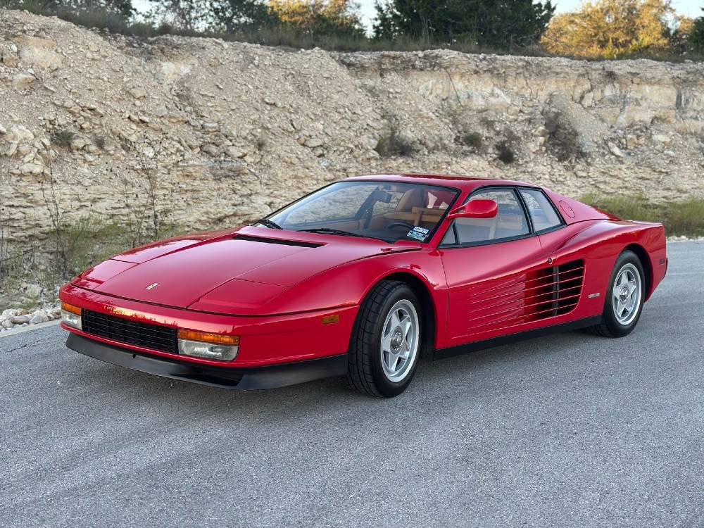 Overhead view of the Ferrari Testarossa taped off next to a cart of Rupes polishers, pads and compounds during multi-stage paint correction at Carsmotology
