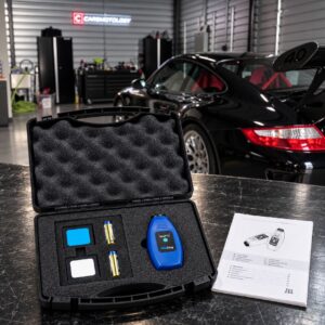NexDiag NexPTG Professional paint thickness gauge in its open case in the Carsmotology shop with a black Porsche
