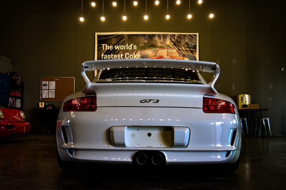 White Porsche 911 GT3 in the Carsmotology shop, the kind of car where measuring paint thickness before buffing matters